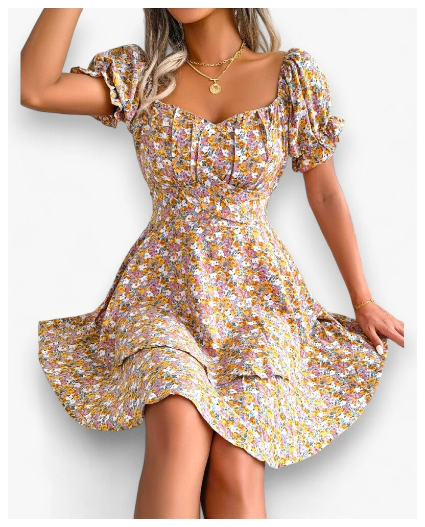 Showcasing a sunny yellow floral print dress for summer parties from Eternal Gleams, a woman poses with elegance. The dress includes puffed short sleeves, a sweetheart neckline, and a fitted bodice flowing into a flared skirt. The cheerful yellow hue brings a fresh and joyful vibe, ideal for warm days. The look is completed with a gold necklace, highlighting the dress’s vibrant and radiant design.